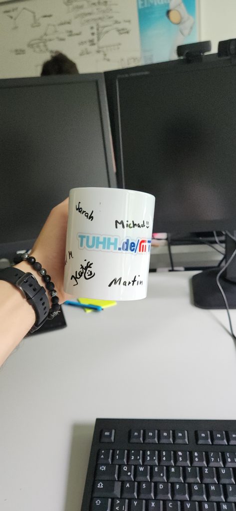 White ceramic coffee cup, covered with handwritten messages from Illia’s friends he met during his internship in Germany